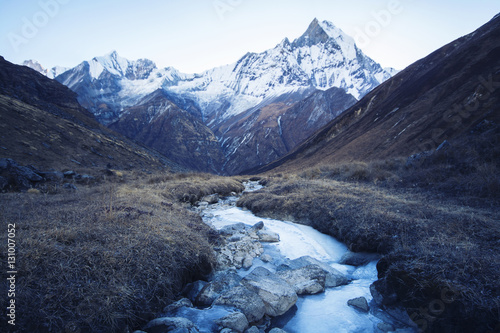 Stream with ice flowing down from the mountains, blue shade of t