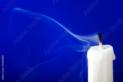 damped candle with smoke on a blue background