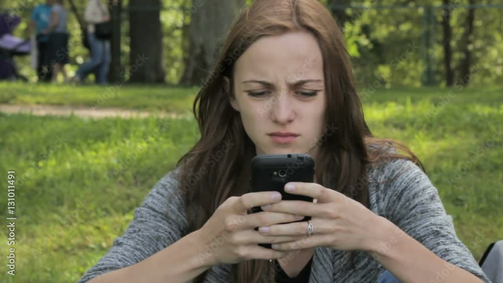 Woman communicates in social networks in a smartphone, in the park Woman communicates in social networks in a smartphone, in the park
