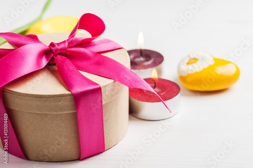 Lit candles and gift box with red ribbon