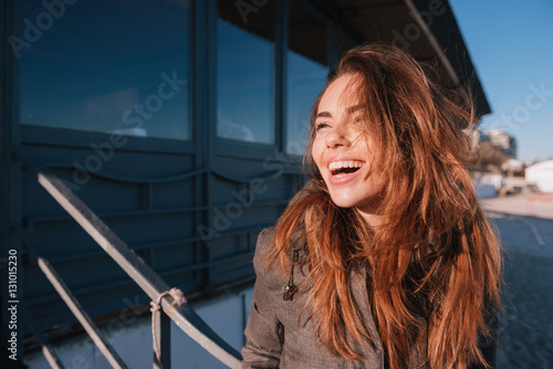 Happy woman in warm jacket on beach near cafe photo