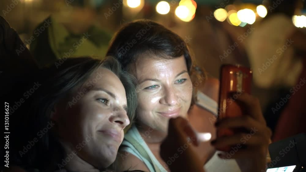Two young girlfriends using smartphone and talking lying in outdoor bar, 4K
Two young girlfriends using smartphone and talking lying in outdoor bar, 4K