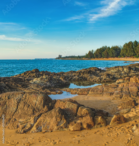 Beautiful seascape with sea and rock in Nang Thong Beach, Khao Lak, Thailand. View of bright blue sea with protruding stones and fishing boats. Nature composition.