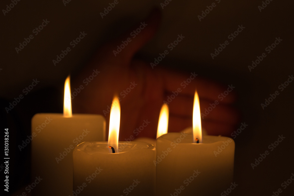 hand behind burning candles hand behind burning candles