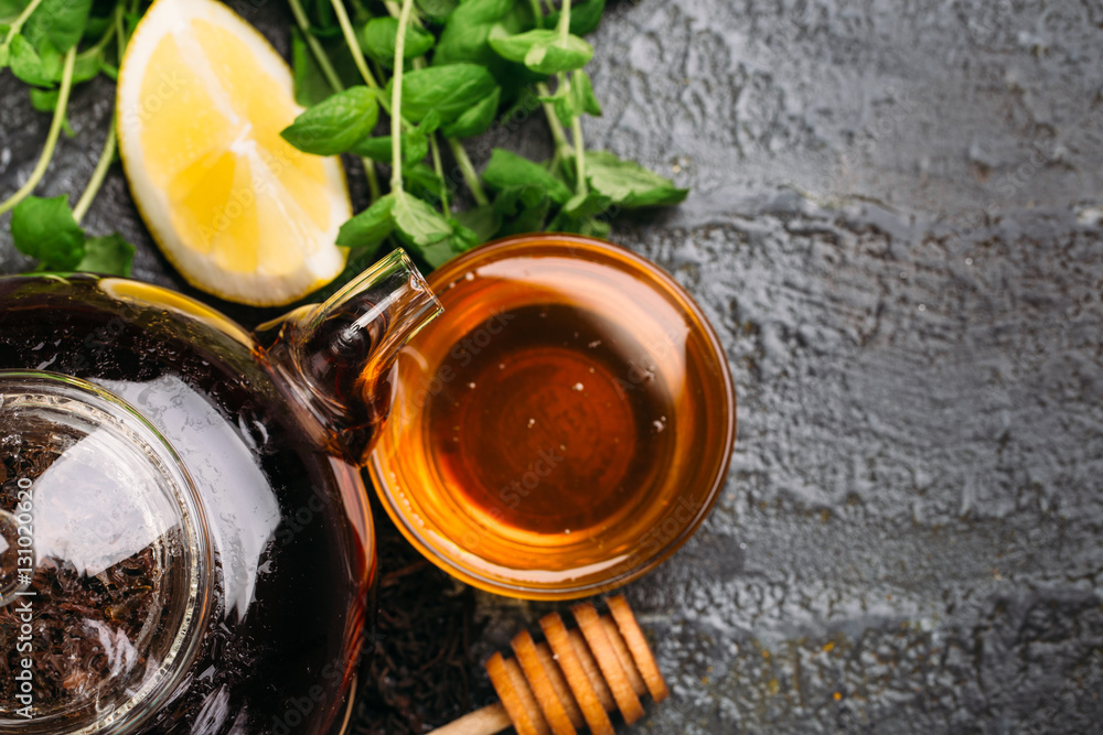 Food background with tea kettle, honey, lemon and mint on black table Top view Food background with tea kettle, honey, lemon and mint on black table Top view