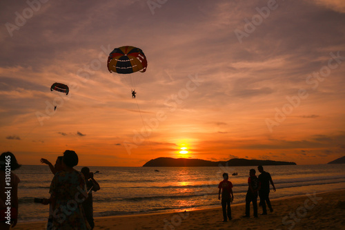 silhouette of parachute and people at the beach