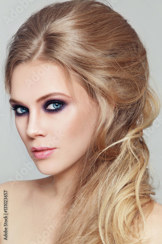 Portrait of young beautiful woman with smoky eyes make-up and stylish messy hairdo