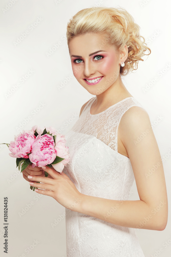 Young beautiful blonde slim happy smiling bride with stylish prom hairdo and bridal bouquet 