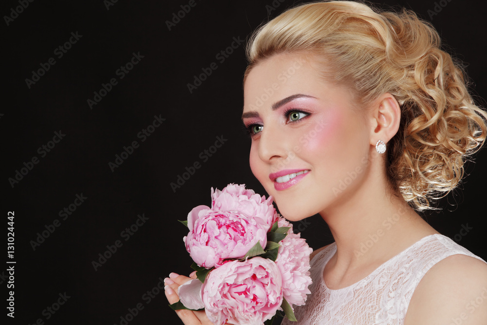 Young beautiful blonde happy bride with stylish prom hairdo and bridal bouquet 