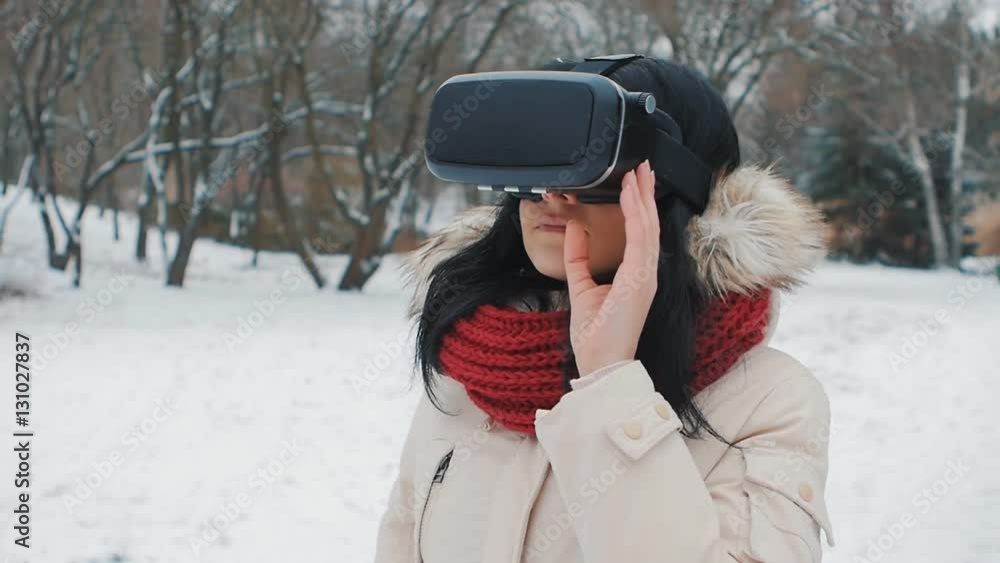 shot of girl getting experience in using VR-headset outdoor at winter park shot of girl getting experience in using VR-headset outdoor at winter park