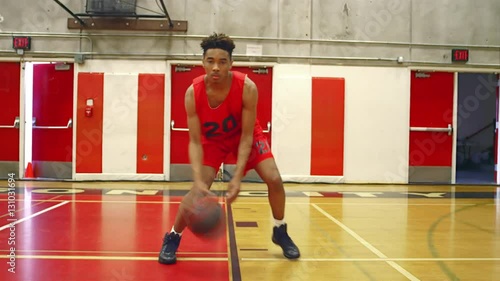 Basketball player dribbling the ball through his legs, toward the camera