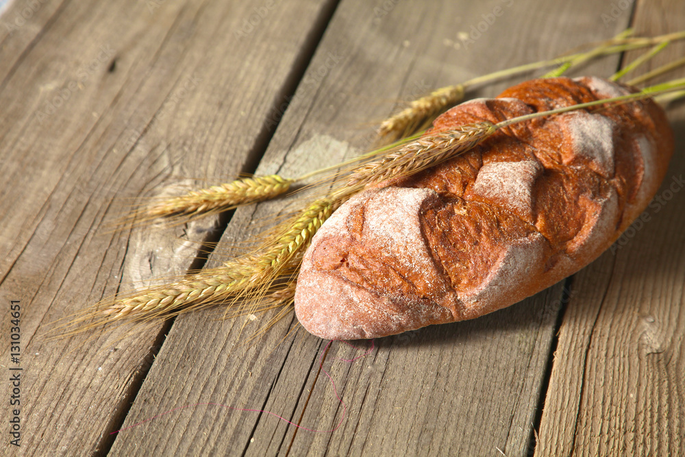rustic crusty bread and wheat ears on a dark wooden table rustic crusty bread and wheat ears on a dark wooden table