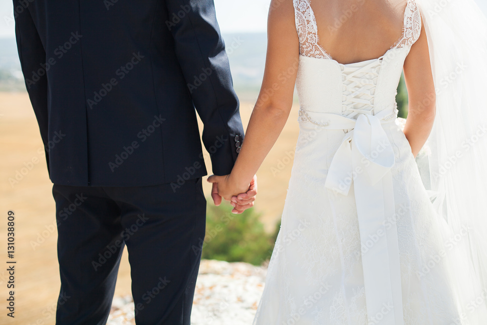 Bride and groom walking together holding their hands Bride and groom walking together holding their hands