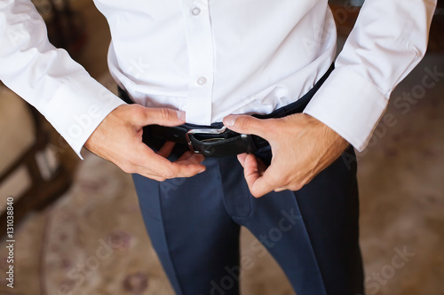 Man corrects belt, fees groom, man's hands, dressing, man button