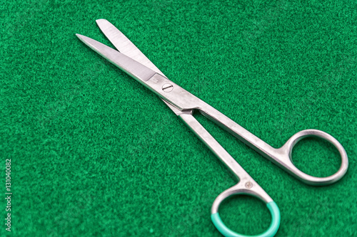 Sterilized real surgical scissors isolated on green background