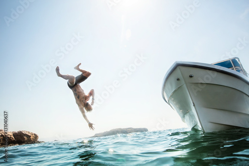 Man flipping off a boat into the ocean.