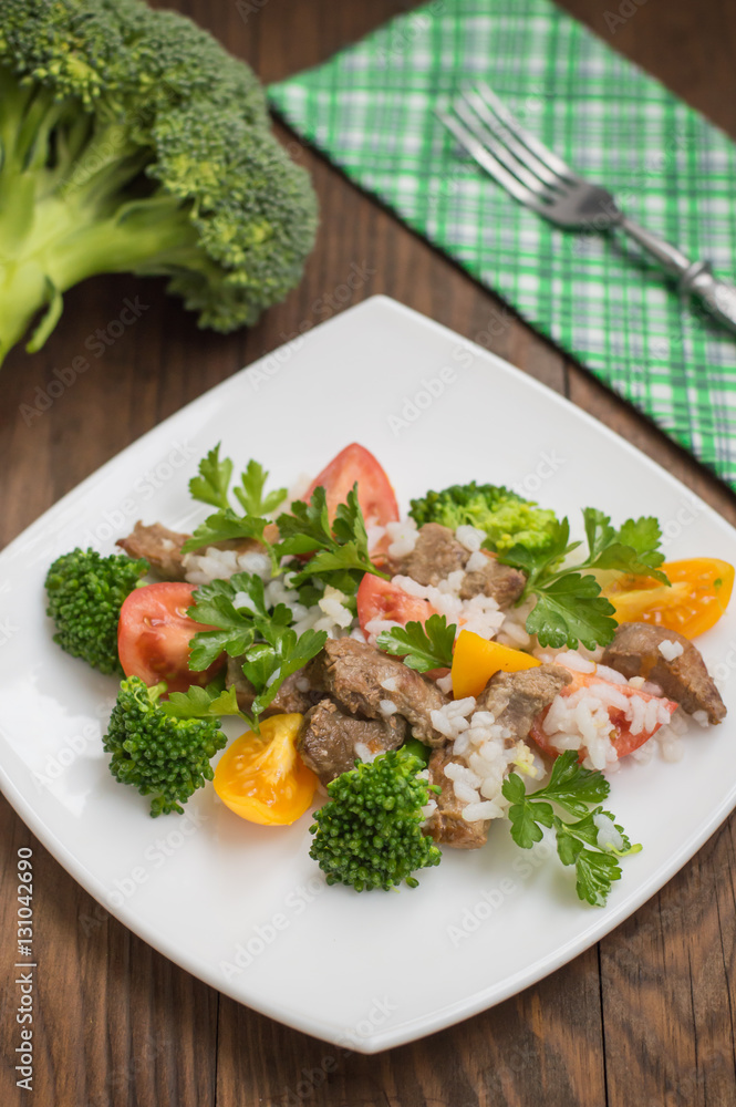 Roasted meat, white rice and vegetables. Wooden background. Top view. Close-up Roasted meat, white rice and vegetables. Wooden background. Top view. Close-up