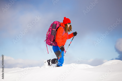 Girl with backpack walking on snow in the mountains.