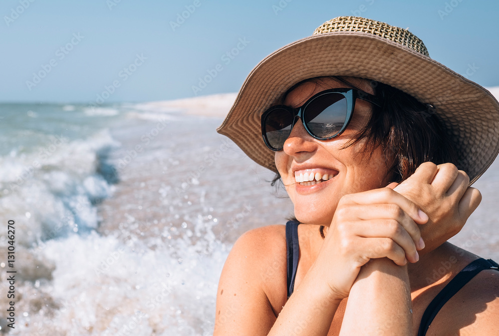 Fototapeta premium Happy smiling woman in straw hat on the sea beach