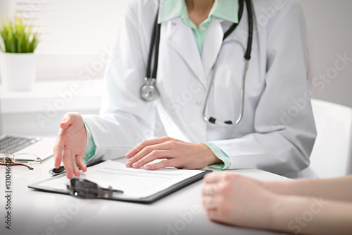 Close up of doctor and  patient  sitting at the desk near the window in hospital