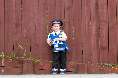 Baby caucasian girl toddler dressing up playing in police unifor