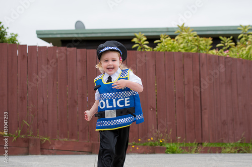Baby caucasian girl toddler dressing up playing in police unifor
