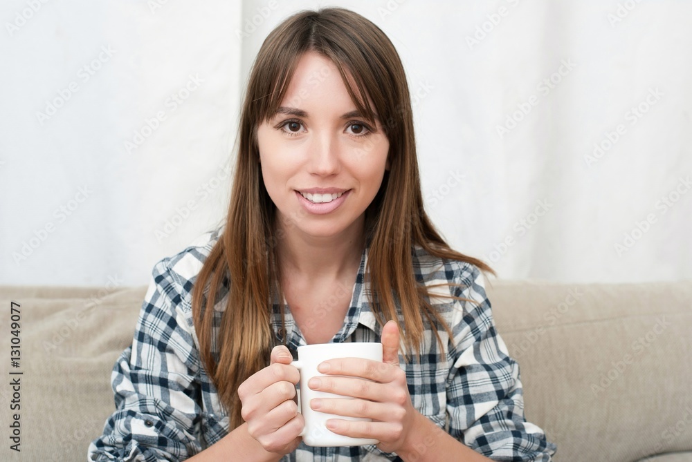 woman sitting on couch in her living room and drinking coffee woman sitting on couch in her living room and drinking coffee