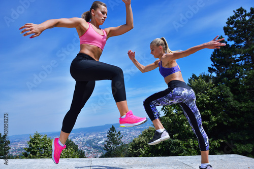 Two happiness young women jumping over blue sky