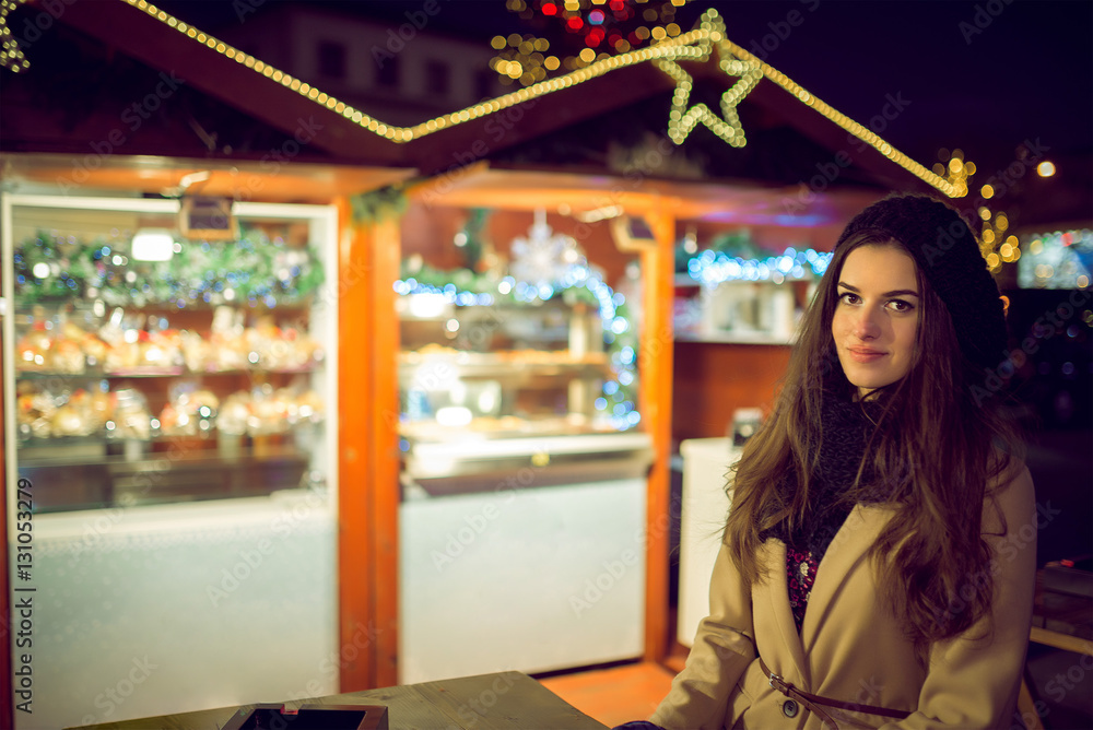 Pretty woman in christmas market during cold evening