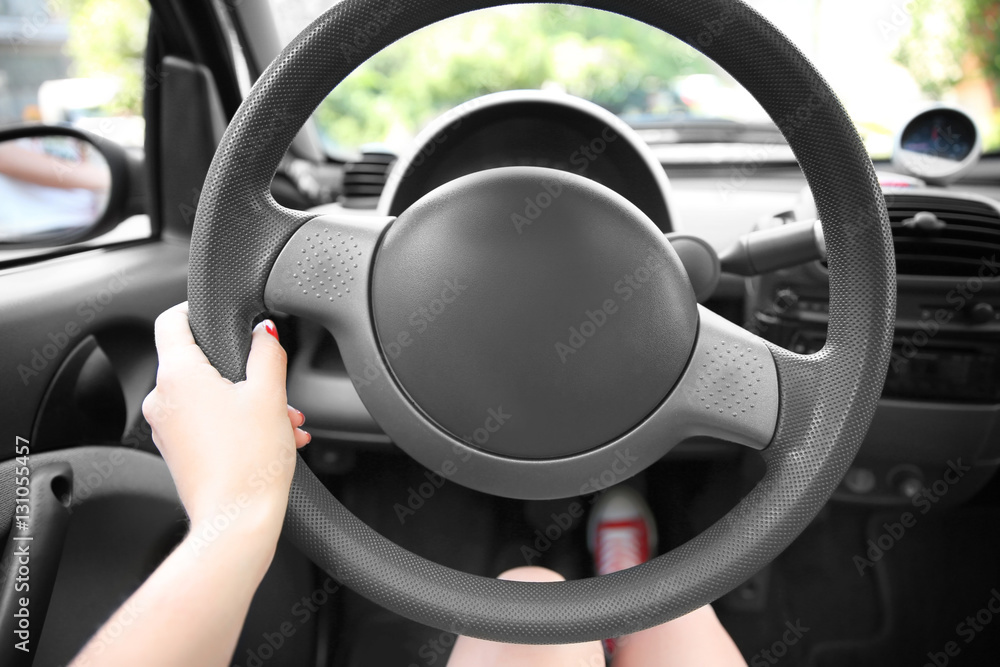 Female hand and steering wheel, closeup