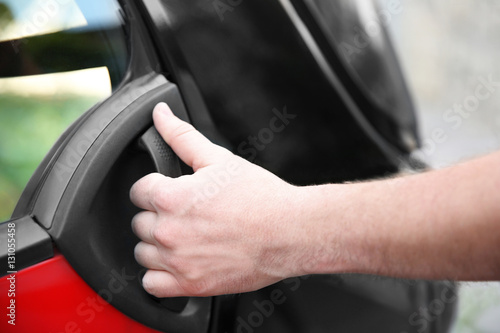 Male hand holding car door handle, closeup