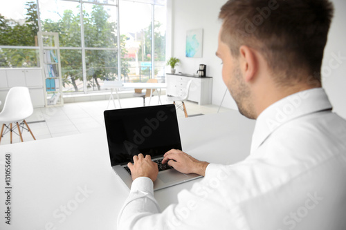 Young man typing on laptop at office