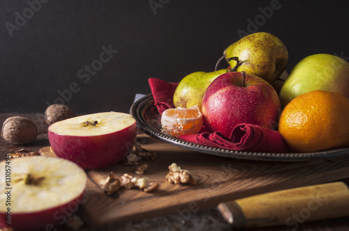 Fresh apple  pear  mandarin  orange and walnut on wooden table