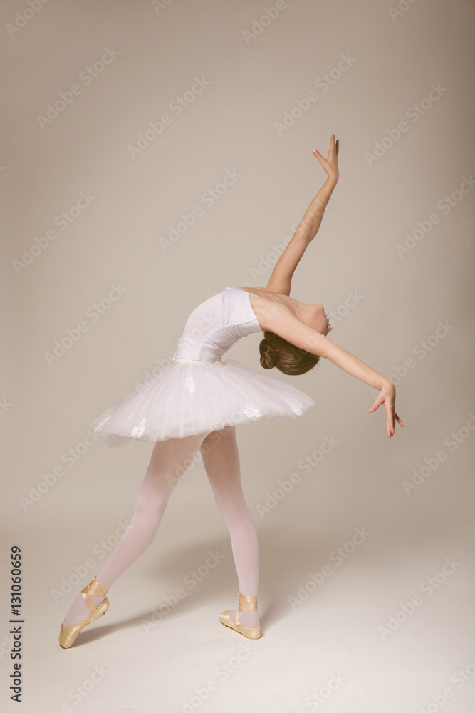 Obraz premium Young beautiful ballerina dancing on light background