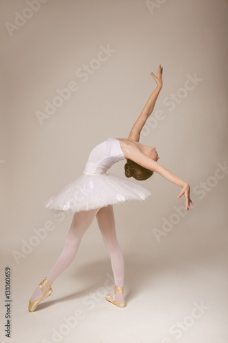 Fototapeta Naklejka Na Ścianę i Meble -  Young beautiful ballerina dancing on light background