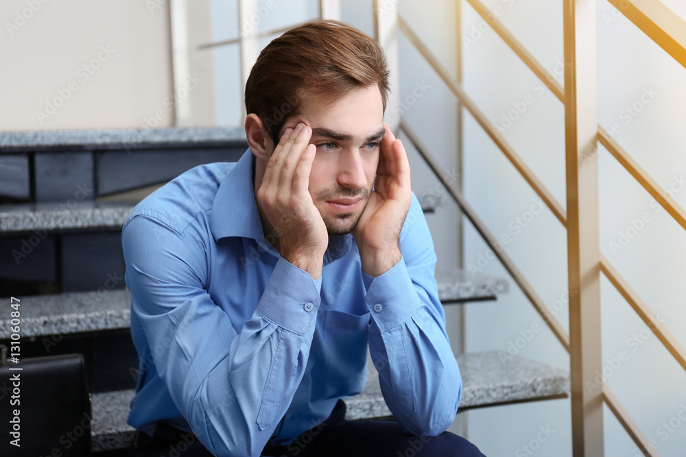 Tired office worker sitting on stairs indoors Tired office worker sitting on stairs indoors