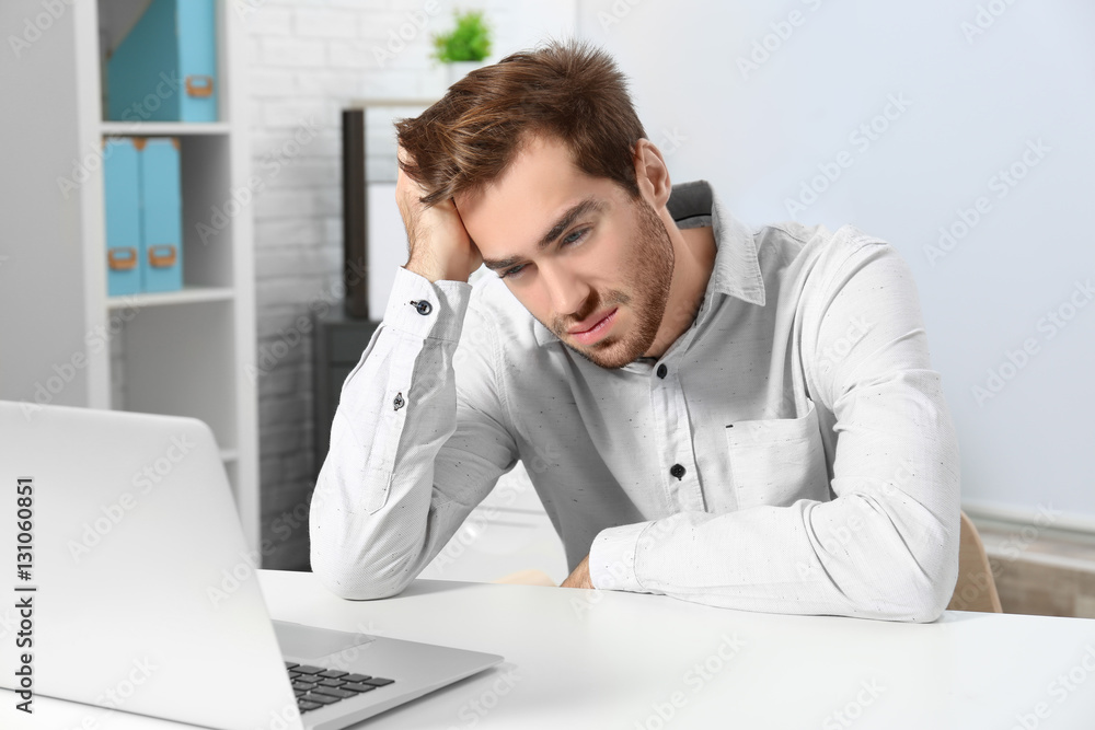 Tired handsome man working with laptop in office Tired handsome man working with laptop in office