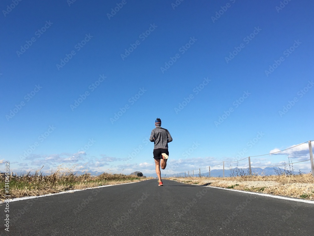 Man running on open country path with winter blue sky - obrazy, fototapety, plakaty 