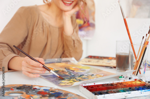 Young female artist painting picture in studio, close up view