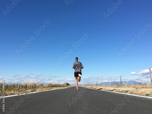 Man running on open country path with winter blue sky