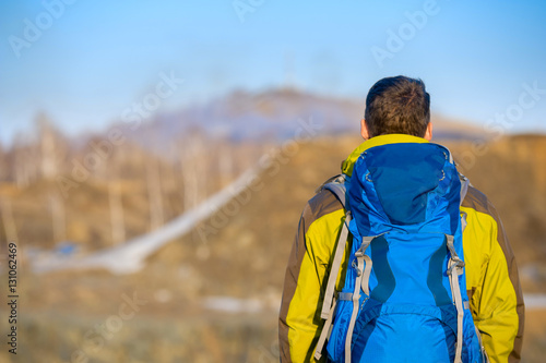 A young man with a backpack looks into the distance
