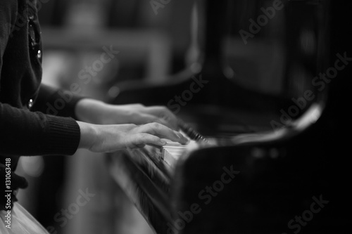 Hands of a child playing the piano closeup in black and white