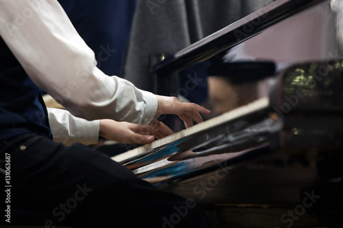 Hands of a child playing the piano closeup in dark colors