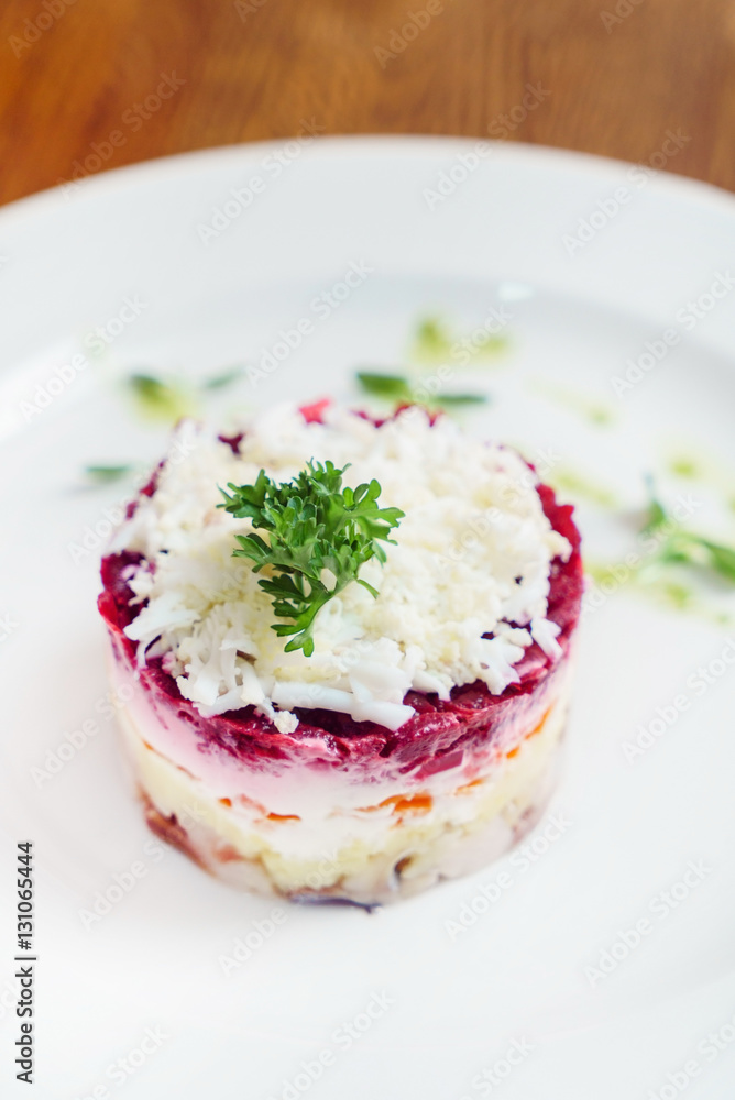 layered salad with herring, beets, carrots, onions, potatoes and eggs close-up on a plate layered salad with herring, beets, carrots, onions, potatoes and eggs close-up on a plate