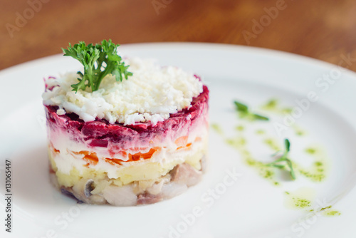 layered salad with herring, beets, carrots, onions, potatoes and eggs close-up on a plate