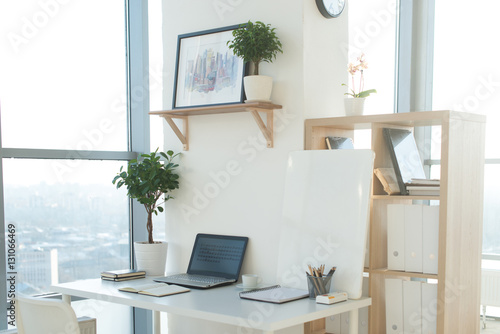 Side view picture of studio workplace with blank notebook, laptop. Designer comfortable work table, home office.