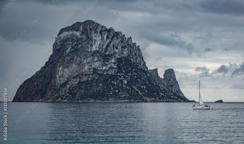The mysterious island of Es Vedra with sailing boat The mysterious island of Es Vedra with sailing boat