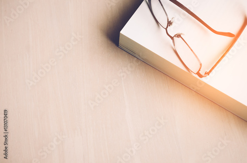 Copy space of book and glasses on wood table background.