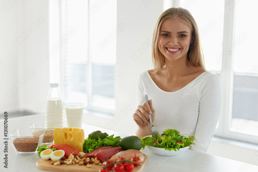 Healthy Nutrition. Beautiful Woman Eating Salad, Foods On Table Healthy Nutrition. Beautiful Woman Eating Salad, Foods On Table