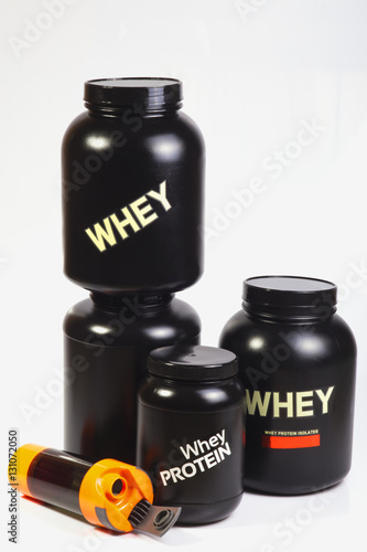 Stock of bodybuilder sports nutrition. Two big black jars with whey protein, one with casein, one more smaller jar with whey protein. . Sport orange shaker near. white background